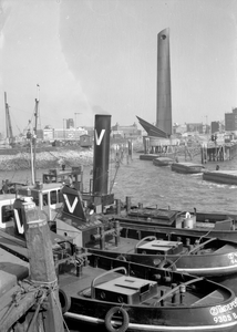 839176 Afbeelding van boten in de Nieuwe Maas te Rotterdam, met op de achtergrond het Nationaal Koopvaardijmonument De ...
